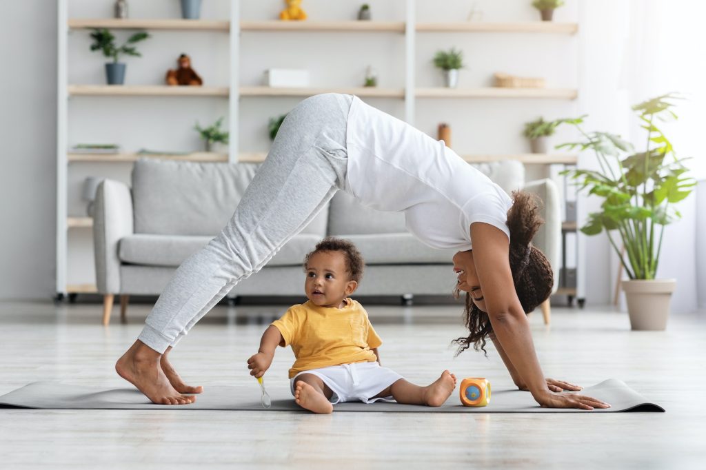 Motherhood And Fitness. Happy Black Woman Exercising With Little Son At Home