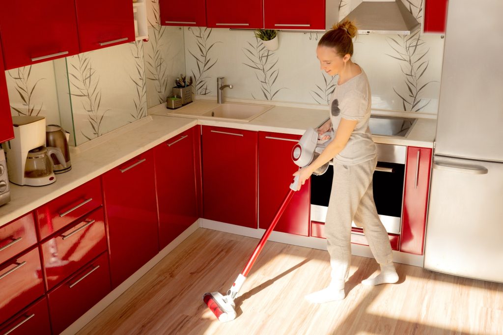 Woman cleaning house with wireless vacuum cleaner.